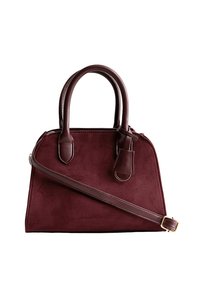 Borsa in suede bordeaux con forma strutturata, doppi manici superiori e tracolla removibile. Presenta un piccolo cartellino in pelle attaccato.