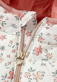 Veste matelassée avec un motif floral en rose et vert. Dotée d'une fermeture éclair dorée avec un tirette en forme de cœur, et d'une doublure intérieure contrastante.