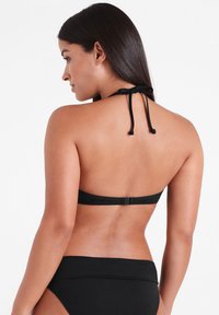 Svart bikini med halterneck-design och spänne. Slät textur med minimalistisk stil. Inkluderar matchande högmidjade underdelar.