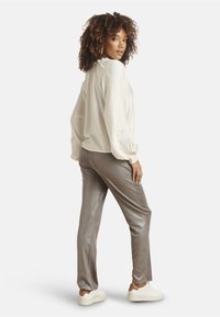 Light beige top with puff sleeves and decorative stitching, paired with metallic silver, straight-leg pants and white sneakers.