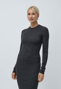 Šedé žebrované šaty s dlouhým rukávem a kulatým výstřihem. Materiál má pletenou strukturu, přiléhavý střih a minimalistický design.