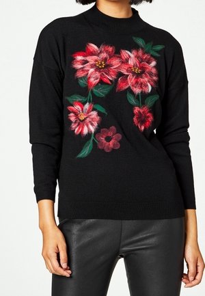 Pull en tricot noir à manches longues avec des broderies florales vives en rouge et rose. Encolure haute et tissu texturé.