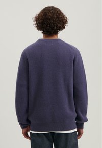Paarse geribbeld sweater met lange mouwen en een ronde hals, met een relaxte pasvorm en textuurstof. Geen zichtbare logo's of accenten.