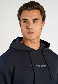Marineblauwe hoodie gemaakt van katoen. Voorzien van een capuchon met trekkoord en een frontlogo in lichtblauw. Soepele textuur, casual pasvorm en geen zichtbare patronen.