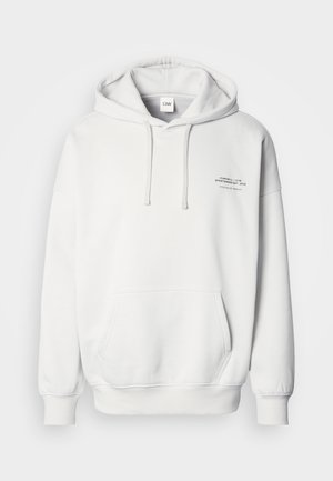 White hoodie with a front pocket, drawstring hood, and printed text on the left side. Features ribbed cuffs and hem, soft fabric texture.