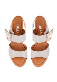Sandales à glissière en cuir blanc avec deux larges sangles, un accent de boucle et des semelles intérieures en cuir beige. Semelles plates avec des détails de couture visibles.