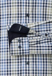Blauw, wit en beige geruite overhemd met lange mouwen en zwarte knopen, opgerolde manchetten die de zwarte binnenstof en knoopgat tonen.