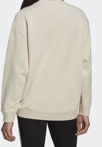Light beige sweatshirt with round neck, dropped shoulders, and long sleeves. Soft fabric with a relaxed fit and ribbed cuffs.