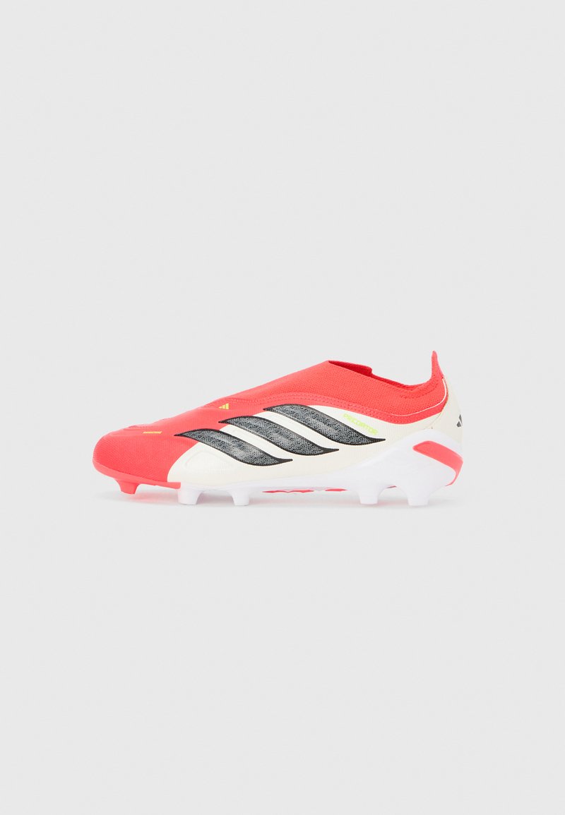 Κόκκινο και λευκό ποδοσφαιρικό παπούτσι Adidas Predator με μαύρες ρίγες και διαμορφωμένες τάπες σε ανοιχτό γκρι φόντο.