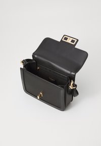 Borsa a mano in pelle nera con forma strutturata, elementi in metallo dorato e chiusura a pattina magnetica. L'interno è dotato di più scomparti.