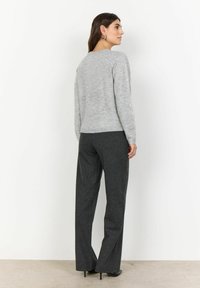 Pullover tricotat de culoare gri deschis, cu mâneci lungi, guler rotund și tiv cu nervuri, asortat cu o pereche de pantaloni modelați gri închis și pantofi cu toc.