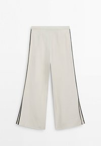 Pantalon ample couleur crème avec des bandes noires sur les côtés et une taille élastique, longueur raccourcie, design à l'avant plat.