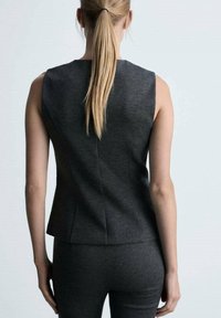 Grijze mouwloze top met een aansluitend ontwerp, voorzien van een hoge hals en subtiele stiksels aan de achterkant, gemaakt van textuurstof.