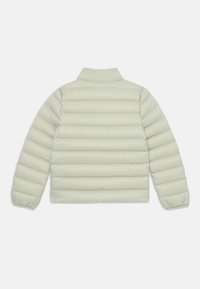 Casaco puffer verde-claro com colarinho curto, design acolchoado e punhos elásticos. Apresenta uma forma rectangular e textura suave, sem hardware visível.