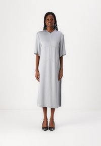 Graues Midikleid mit V-Ausschnitt, kurzen Ärmeln und Seitenschlitzen. Hergestellt aus glattem Stoff mit kontrastierenden Nähten und einer lockeren Passform.