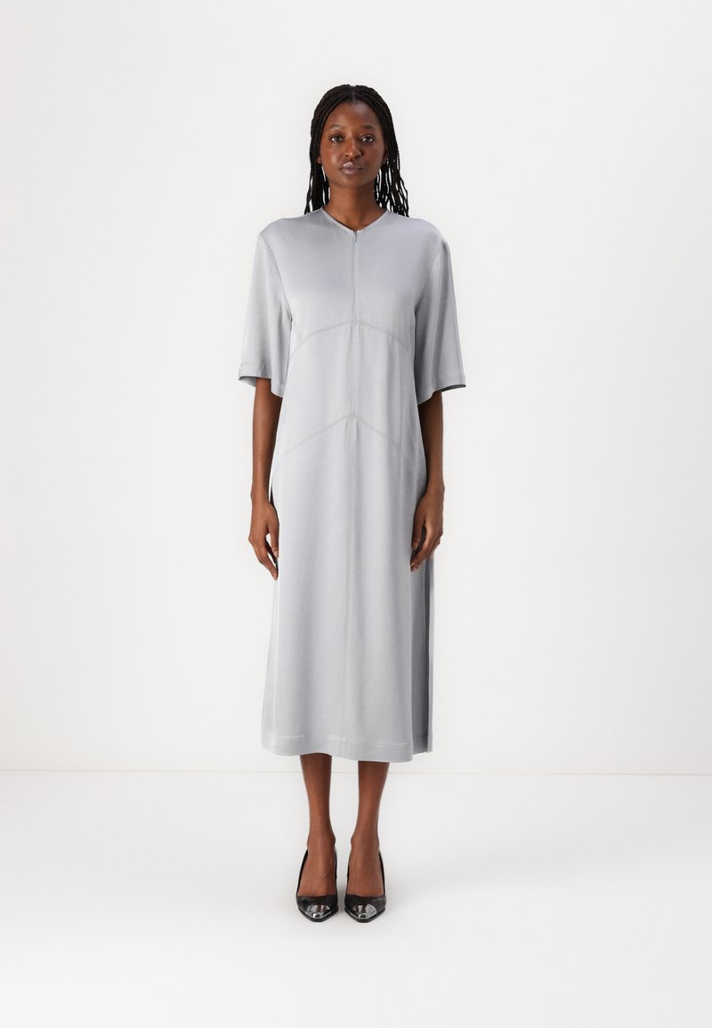 Graues Midikleid mit V-Ausschnitt, kurzen Ärmeln und Seitenschlitzen. Hergestellt aus glattem Stoff mit kontrastierenden Nähten und einer lockeren Passform.