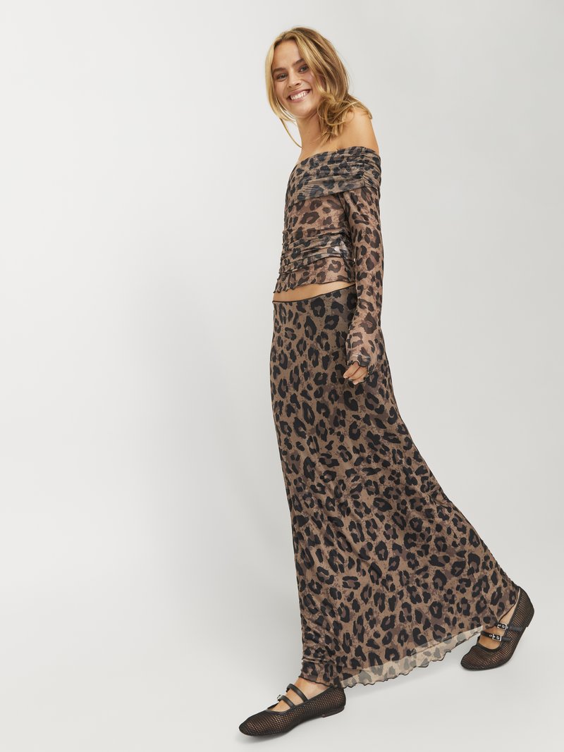 Zestaw składający się z bluzki bez ramiączek w panterkę i długiej spódnicy. Przezroczysty materiał z falbanami na dole. Czarne płaskie buty z krzyżującymi się paskami.