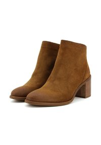 Stivaletti in suede marrone con punta arrotondata e tacco spesso. La texture è morbida, con una finitura liscia e senza cuciture visibili.