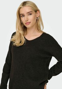 Maglione nero lavorato a maglia con scollatura a V, tessuto texture e maniche lunghe, con una vestibilità morbida e dettagli a coste sottili.
