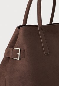 Brown suede tote bag with two sturdy handles, featuring a rectangular shape and a silver-tone hardware accent near the top.