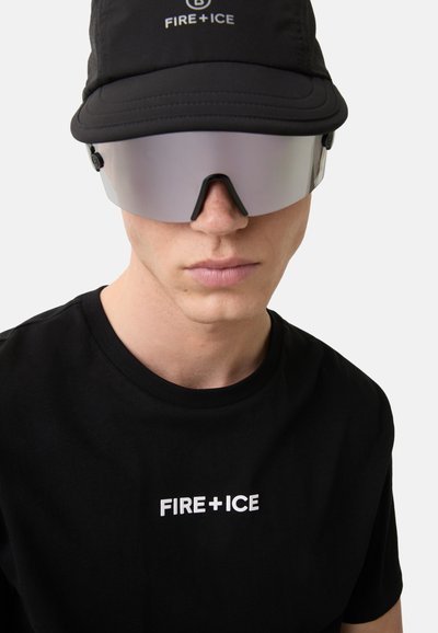 Černé bavlněné tričko s logem "FIRE+ICE" v bílé barvě, kombinované s černou čepicí a slunečními brýlemi s reflexním zorníkem. Minimalistický design.