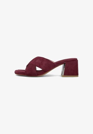 Sandalia mule de mujer con tacón, con tiras cruzadas de ante burdeos y tacón ancho con detalle plateado sobre fondo blanco.