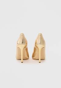 Chaussures à talons hauts dorées avec une finition en cuir texturé brillant, design à bout pointu et talon aiguille élancé. Détail du logo à l'arrière.