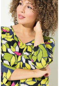 Multikleurige blouse met een levendig bladdessin in groen, roze en marineblauw, met een V-hals en driekwart mouwen, gemaakt van lichtgewicht stof.