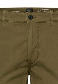 Olivegrüne Hose mit Knopfverschluss, Gürtelschlaufen und sichtbaren Nahtdetails im vorderen Taillenbereich.
