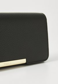 Black leather wallet with a textured finish and a gold-tone logo plate. Features a sleek, rectangular design with rounded edges.