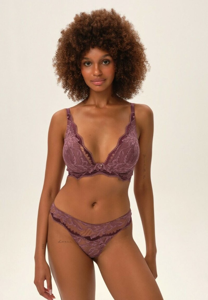 Lace bra and matching thong in mauve, featuring floral patterns, scalloped edges, and adjustable straps. Soft, textured fabric detail.