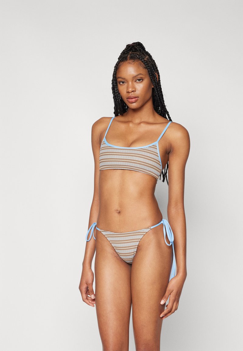 Set di bikini a righe marrone e blu, con un top bandeau a spalline sottili e uno slip annodato. Il materiale ha un aspetto testurizzato.