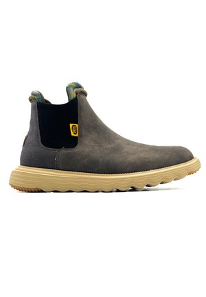 Stivaletti in suede marrone con un pannello elastico nero, pull sul tallone testurizzato e suola in gomma beige con un motivo ondulato e un'etichetta con logo.