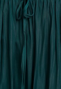 Teal gathered skirt with a drawstring waist, made from lightweight fabric featuring a smooth texture and subtle sheen.