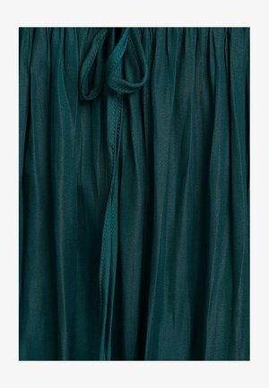 Žydra suknelė su raišteliu juosmenyje, pagaminta iš lengvos medžiagos, turinčios lygią tekstūrą ir subtilų blizgesį.