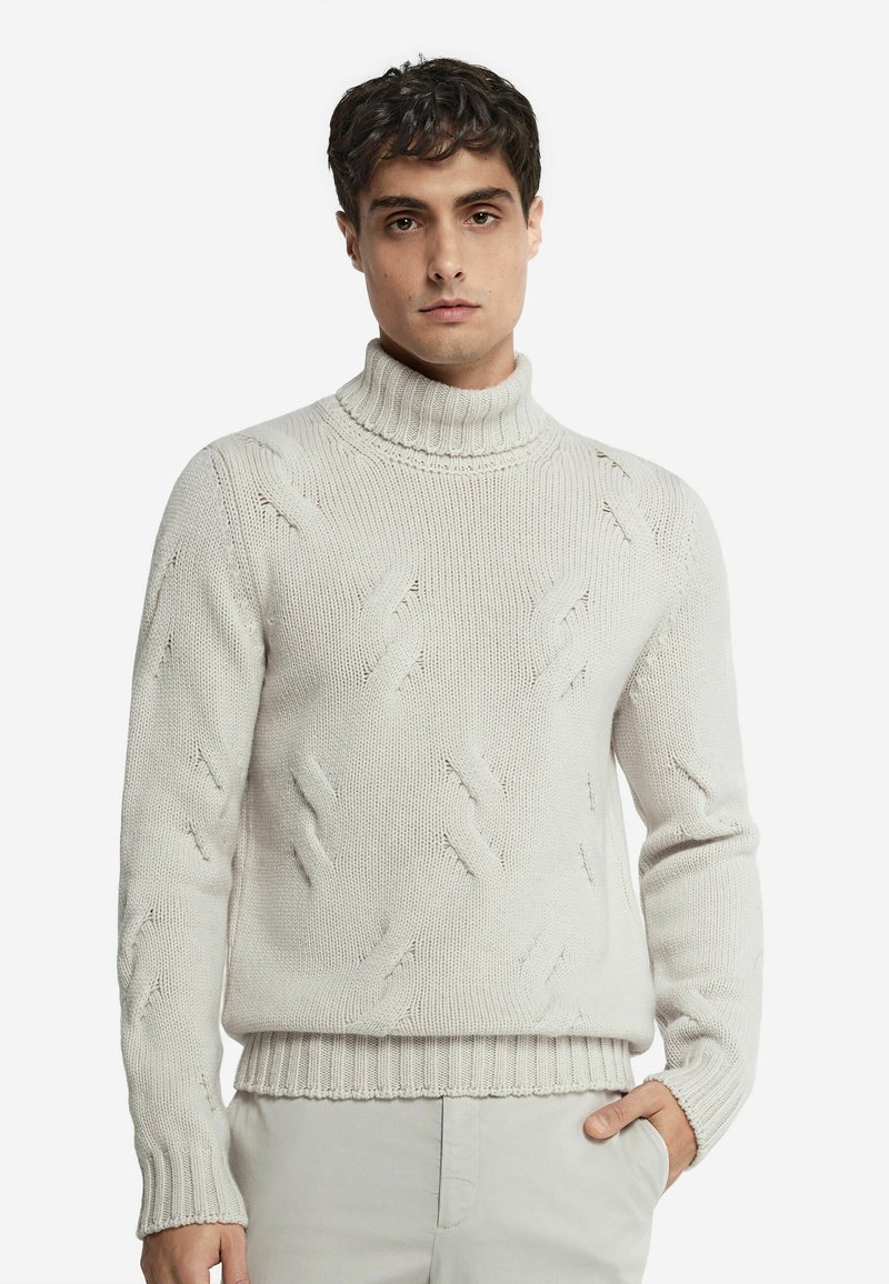 Ljusbeige stickad tröja med hög ribbad krage, som har ett strukturerat mönster och ribbade ärmslut och nederkant. Tillverkad av ett mjukt tyg.