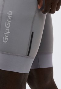 Κοντινό πλάνο ενός ατόμου που φοράει ανοιχτό γκρι σορτς ποδηλασίας GripGrab, τονίζοντας το υφασμάτινο μοτίβο και τις ραφές.