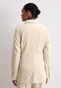 Crème kleurige corduroy blazer met een ribbeltextuur, notch-kraag en lange mouwen. Heeft een gestructureerde pasvorm en een ventileerde achterkant.