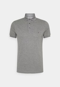 Grå polo tröja av mjuk bomull, med krage, tre knappar och en liten logotyp på vänstra bröstet.