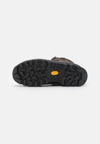 Fottøy såle med dype, robuste svarte gummimønster for grep. Har en gul Vibram-logo i midten for forbedret grep.