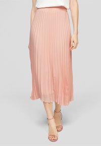 Skládaná midi sukně z měkké růžové látky, s přiléhavým pasem a volným střihem. Kombinováno s páskovými tělovými podpatky.