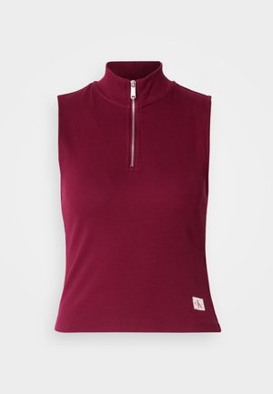 Bezrūšu, pieguļošs tops dziļi burgundijas krāsā, ar augstu apkakli un priekšējo rāvējslēdzēju. Gluda auduma ar logotipa uzšuvi apakšējā kreisajā stūrī.