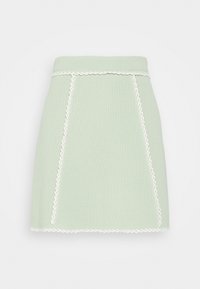 Pletená sukně v mentolově zelené barvě s texturovanou tkaninou, bílý prošívaný lem podél kapes a spodního okraje, přiléhavý styl a rovný silueta.