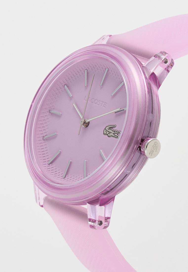 Orologio rosa in plastica con quadrante testurizzato, indicatori delle ore in argento e logo Lacoste. Presenta un cinturino in silicone morbido per il massimo comfort.