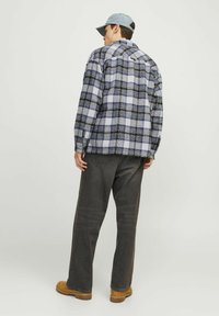 Ruteklædt flannel skjorte i blå, sort og hvid. Løs pasform med sænket skuldre. Sammen med mørke bukser og brune støvler. Blå kasket båret baglæns.