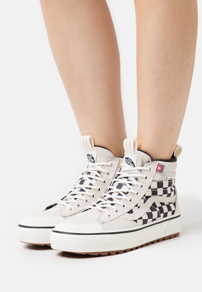 Höga sneakers i kanvas i krämfärgad med svart rutmönster, vita snören, gummisålar och varumärkeslogotyp på tungan.