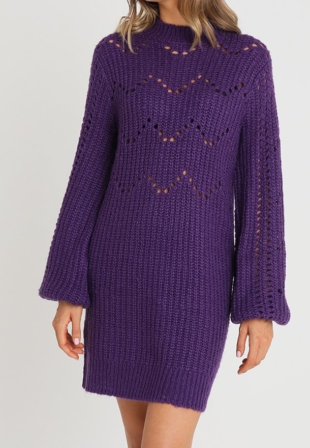 Robe-pull tricotée violette à manches longues avec motif chevron en maille ajourée et ourlet côtelé, portée par une femme aux cheveux lâchés.