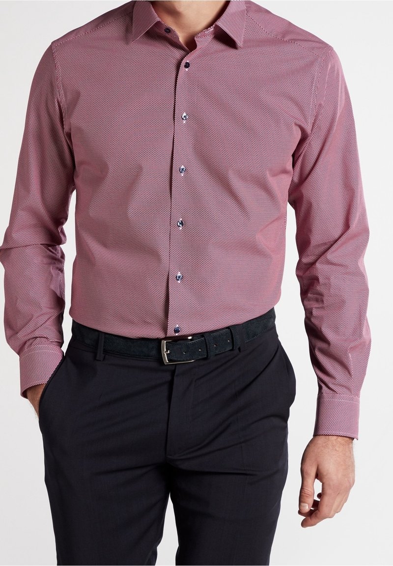Rood en wit gestreept overhemd met lange mouwen en een button-down kraag, met donkere knopen en een eenvoudige zwarte riem met een zilveren gesp.