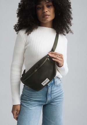 Olivgrüner Bauchtasche aus Canvas mit Reißverschluss, rechteckiger Form und einem Logolabel. Wird um die Taille getragen.