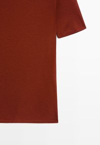 Kurzärmeliges T-Shirt in Rostfarbe aus weichem, glattem Stoff mit rundem Ausschnitt und sauberem Saum. Einfaches Design ohne sichtbare Muster oder Verzierungen.